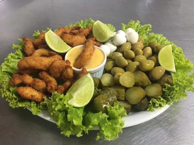 Porção com iscas empanadas, azeitonas, pepino, ovos de codorna e limão